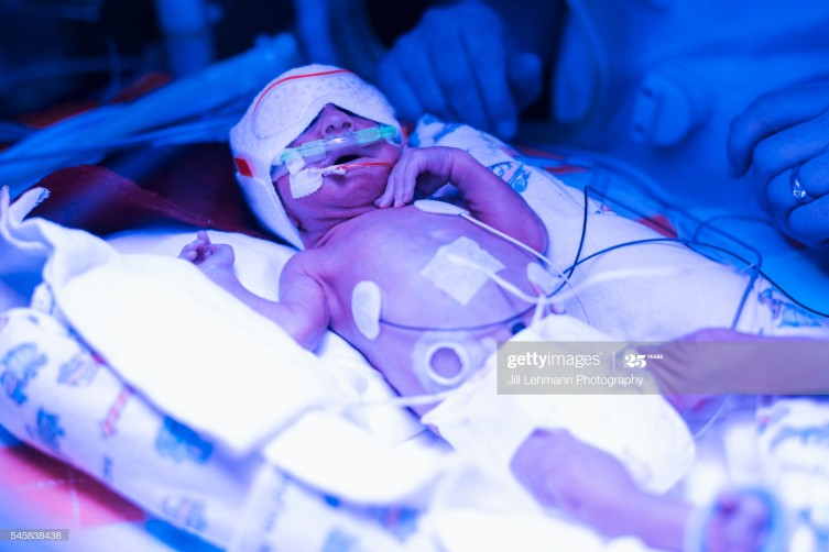 NICU baby is tended to in his isolette