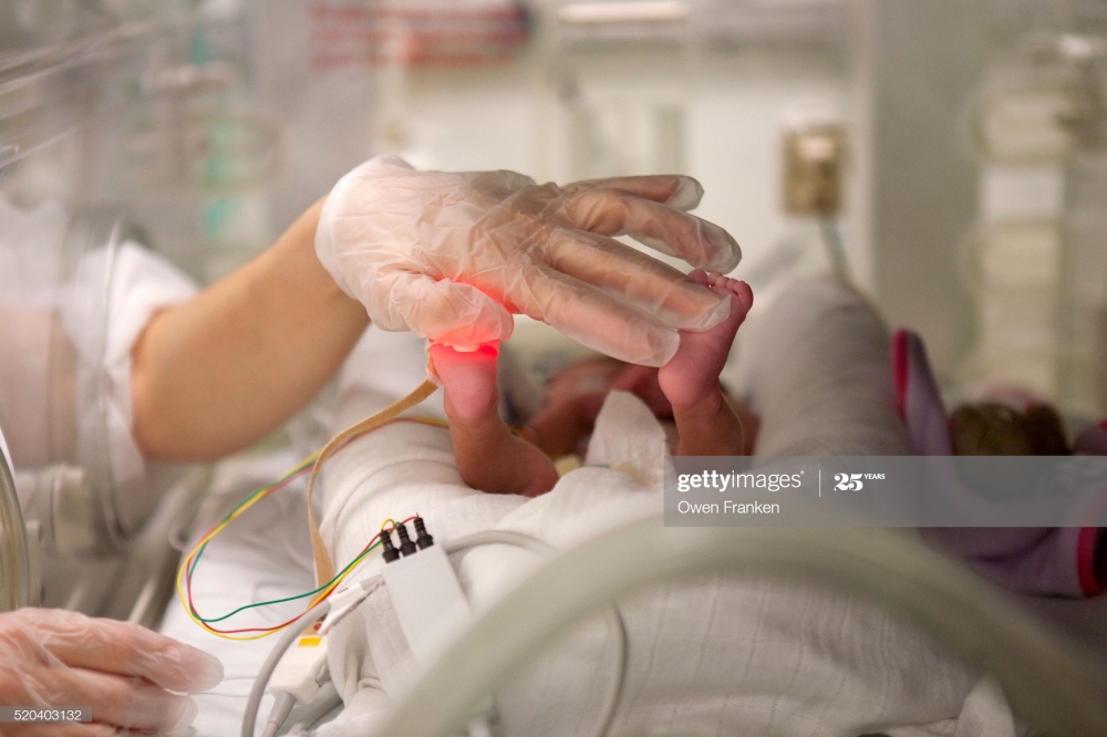 nurse checking up on a premature baby in incubator in a hospital